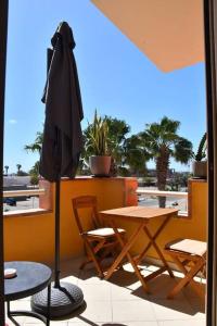 a patio with a table and chairs and an umbrella at Kyaala Djadsal Moradias pool&sea in Santa Maria