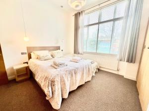 um quarto com uma cama e uma grande janela em Stylish 2BR Designer Flat Holland Park em Londres