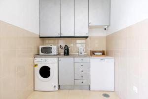 a kitchen with a washing machine and a microwave at Villa Lucia, Olhos D'Agua, Albufeira in Albufeira