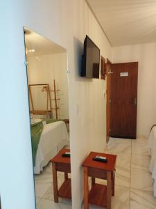 a room with a bed and a table and a door at Japaratinga Suites in Japaratinga
