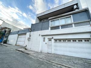 a white building with two garage doors on a street at Makati Altean Apartment (Delfin Room) in Manila
