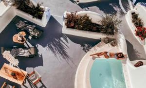 an overhead view of a pool with two women laying on the tub at Sun Angelos Oia - Luxury Cave Suites in Oia