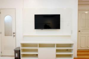 a living room with a tv on a white wall at Makati Altean Apartment (Leonora Room) in Manila