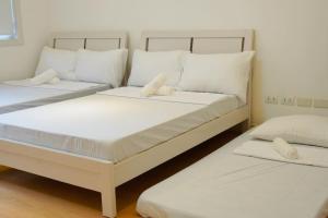 2 Betten mit weißer Bettwäsche und Kissen in einem Zimmer in der Unterkunft Makati Altean Apartment (Leonora Room) in Manila