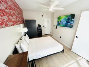 een slaapkamer met een wit bed en een plafondventilator bij Greenview Hotel By Lowkl in Miami Beach