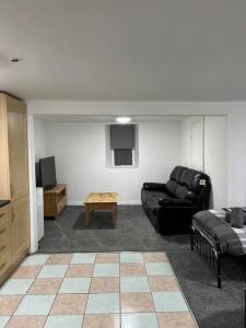 a living room with a black couch and a table at Studio Flat Twin - Town Centre in Merthyr Tydfil