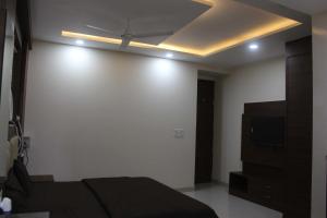 um quarto com uma cama, uma televisão e um tecto em OYO Hotel Daffodils Near Aravali Biodiversity Park em Gurgaon