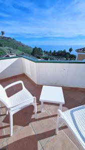 a patio with two white chairs and a table at Nerja Villas Tamango Hill 5 Silhouse in Torrox