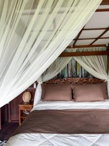 ein Schlafzimmer mit einem Himmelbett in der Unterkunft Karyasari kabin - Tiny House in Blimbing