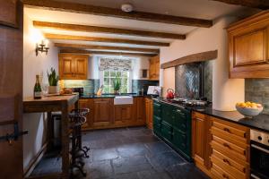 a kitchen with wooden cabinets and green counters at Carrholme Cottage in Settle