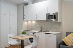 a kitchen with white cabinets and a table with chairs at InsideHome Palencia Catedral in Palencia