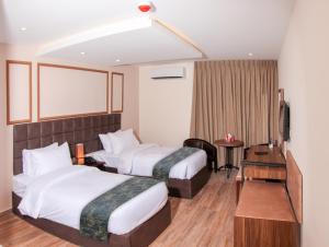 una habitación de hotel con dos camas y una mesa en POST Hotel Amman, en Amán 27 fotos más