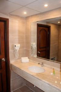 Un baño con lavabo y un espejo grande. en POST Hotel Amman, en Amán