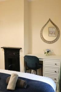 een slaapkamer met een bed, een bureau en een spiegel bij Comfortable 2 Bedroom House in Beeston Hill
