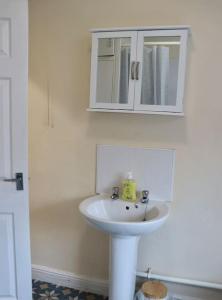 a bathroom with a white sink and a cabinet at Comfortable 2 Bedroom House in Beeston Hill