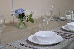 a table with glasses and plates and a vase of flowers at Comfortable 2 Bedroom House in Beeston Hill