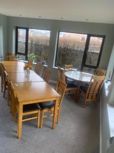 un comedor con mesas y sillas de madera y ventanas en Polrudden, en Islas Orcadas