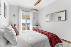 a white bedroom with a large bed and a window at On The Port: Studio in Rafina