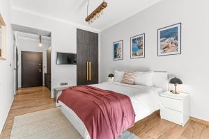 a white bedroom with a large bed and a tv at On The Port: Studio in Rafina