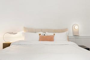 uma cama grande com lençóis brancos e almofadas em Central London Apartment em Londres