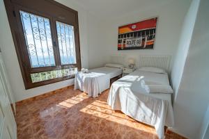 two beds in a room with a window at HomeHolidaysRentals Malvina in Pineda de Mar