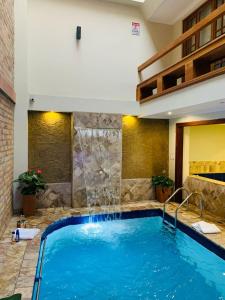 una piscina con cascada en una habitación de hotel en Magdalena Hotel & Suites en Cuenca