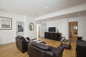 Sala de estar con 2 sofás de cuero y TV en Lovely South Kensington Flat en Londres