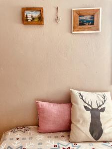 un letto con cuscino e due immagini sul muro di Azzurro Mountain Lodge 