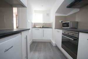 a kitchen with white cabinets and a microwave at Lovely South Kensington Flat in London
