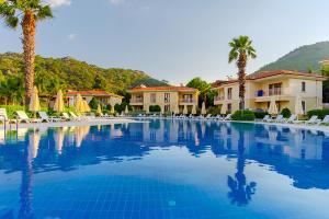 a large swimming pool with palm trees and houses at The One Club Hotel in Sarigerme