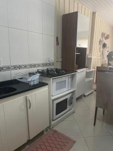 uma cozinha com armários brancos e um forno com placa de fogão em Casa 01,02 em Bombinhas