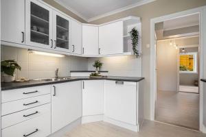 a kitchen with white cabinets and black counter tops at Flott sentral 3 roms leilighet in Bergen