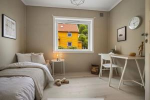 a bedroom with a bed and a table and a yellow house at Flott sentral 3 roms leilighet in Bergen