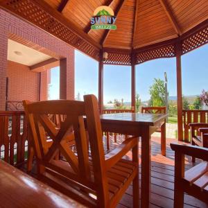 a wooden pavilion with a wooden table and chairs on a deck at Sunny Breeze in Karakkulʼtugay