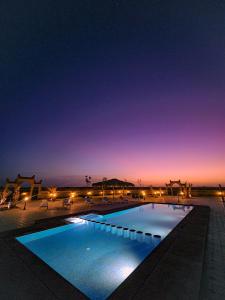 una piscina por la noche con las luces encendidas en Berber Palace Merzouga, en Merzouga