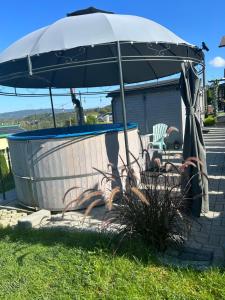 an umbrella sitting next to a tub in the grass at Amaretto Apartamenty-Solina z sauną i ruską banią in Solina