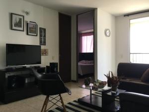 uma sala de estar com uma cadeira preta e uma televisão em Apto amoblado en valle del lili en la ciudad de Cali em Cali