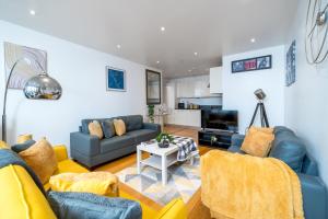 a living room with blue couches and a table at LUX CONDO for 5 Slough Elizabeth line free parking in Slough