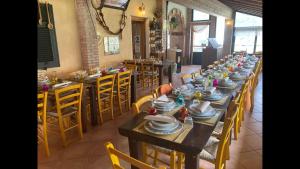 a dining room with long tables and chairs with dishes on them at Agriturismo LA TAVERNA DEL NONNO in Borzonasca