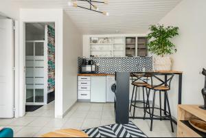 a kitchen with white cabinets and a counter with stools at Maisonnette Jardin Merignac in Mérignac