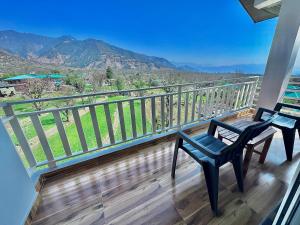 a balcony with two chairs and a view of the mountains at The Billing Health Resort in Bīr