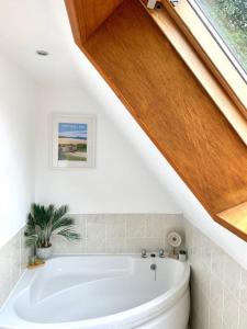a bathroom with a white bath tub in a attic at Hideaway Lodge Hengar Manor 4 bed sleeps 8 to10 in Michaelstow