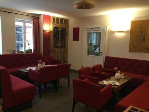 um restaurante com sofás vermelhos, mesas e cadeiras em Fachwerk-Hotel Eisenbart em Hannoversch Münden