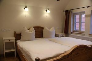 um quarto com uma cama com lençóis brancos e almofadas em Fachwerk-Hotel Eisenbart em Hannoversch Münden