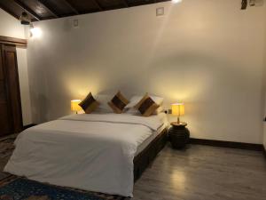 a bedroom with a large bed with two lamps at Private Villa by Rashuthere in Rasdu