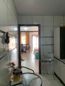 une cuisine avec une table en verre et une chambre dans l'établissement Casa em condomínio com churrasqueira, à Cabo Frio
