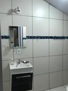 La salle de bains blanche est pourvue d'un lavabo et d'un miroir. dans l'établissement Casa em condomínio com churrasqueira, à Cabo Frio