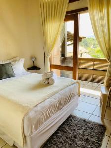 a bedroom with a large bed and a large window at Silveira Eco Village Residence in Garopaba