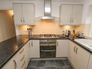 uma cozinha com armários brancos e um forno com placa de fogão em The Squirrels em Hebden Bridge