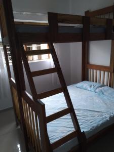 a wooden bunk bed with a ladder leading to a bed at casa de praia in Guaratuba